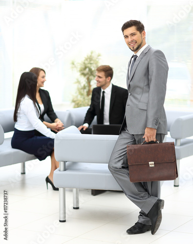 Successful business man standing with his staff in background at