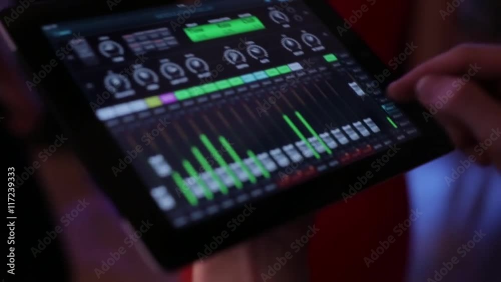The DJ controls the music with the tablet and equalizer, The DJ controls the music with the tablet and equalizer,