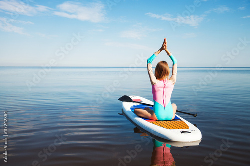 Woman doing yoga on sup board with paddle photo