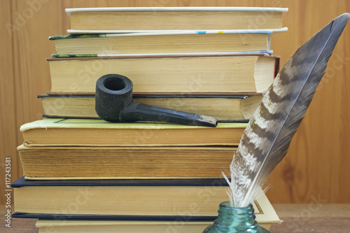 Vintage still life: old books, pen with ink jar and smoking pipe.