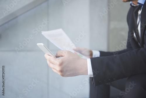 Busy man with smartphone and some documents