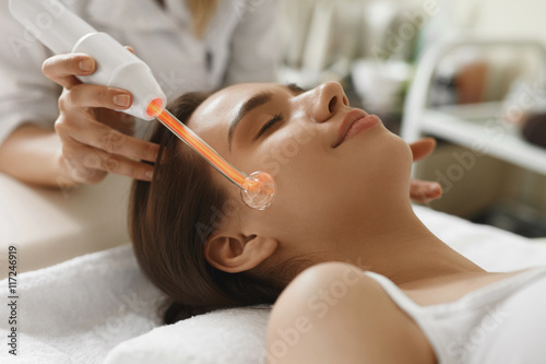 Face Beauty Treatment. Woman Using Darsonval Skin Care Device photo