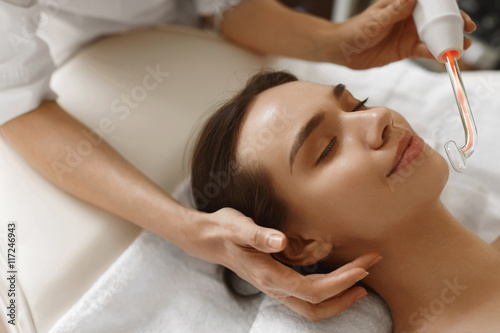 Face Beauty Treatment. Woman Using Darsonval Skin Care Device photo