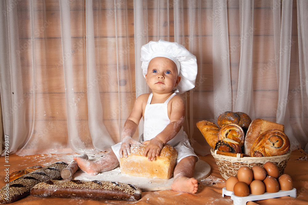 Happy baby baker sitting surrounded by bread and pastries Happy baby baker sitting surrounded by bread and pastries