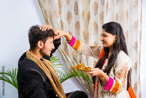 Indian young sister tying rakhi on brother's wrist, a tradition on Raksha Bandhan festival