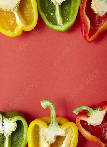 Murais de parede Colorful sweet bell pepper halves on a red background forming a page frame