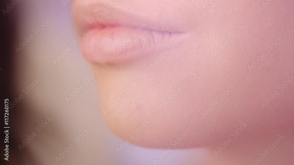 Extreme close up on models lips when visagist applying makeup. Professional fashion beauty make-up. Perfect lips and skin