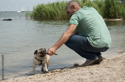 Stoere volwassen man speelt met hond op het strand photo