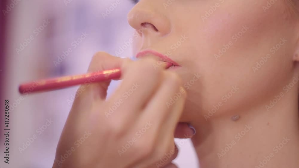 Make up artist applying lipstick with brush on pretty gorgeous woman lips. Closeup of visagiste and young girl. Beauty and makeup concept. Make up artist applying lipstick with brush on pretty gorgeous woman lips. Closeup of visagiste and young girl. Beauty and makeup concept.