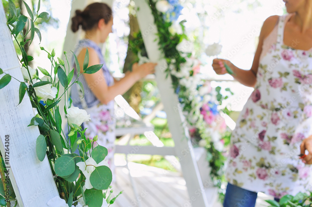 Florist woman at work decorating beautiful wedding arc outdoors, selective focus Florist woman at work decorating beautiful wedding arc outdoors, selective focus