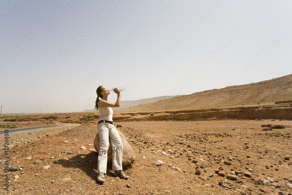 Fototapeta premium femme dans le désert qui boit de l'eau
