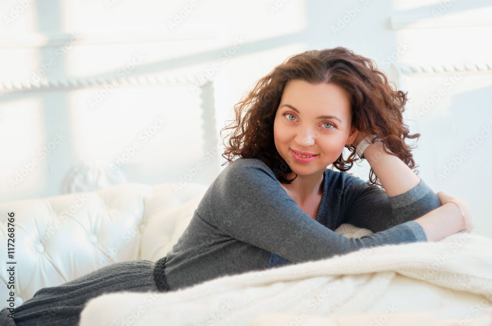 portrait of gorgeous young woman sitting in a white couch portrait of gorgeous young woman sitting in a white couch