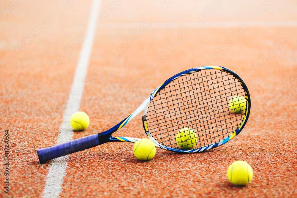 tennis racket with many balls on clay court..