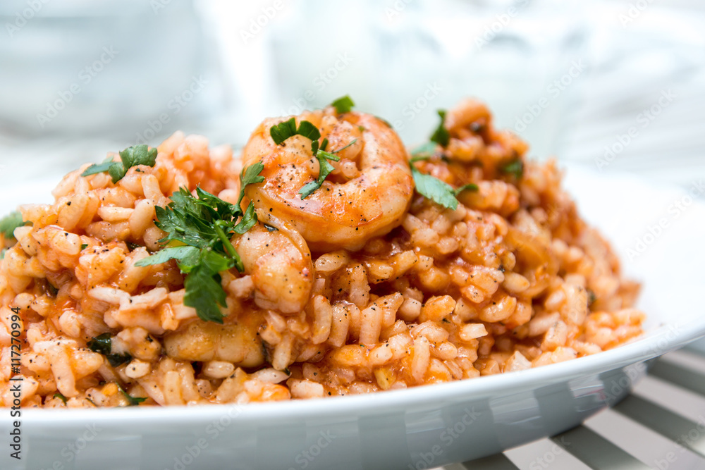 Tasty risotto with Shrimp, fresh herbs vegetables on a white pla Tasty risotto with Shrimp, fresh herbs vegetables on a white pla