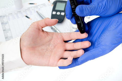 Pricking a finger with lancet to measure blood glucose amount.