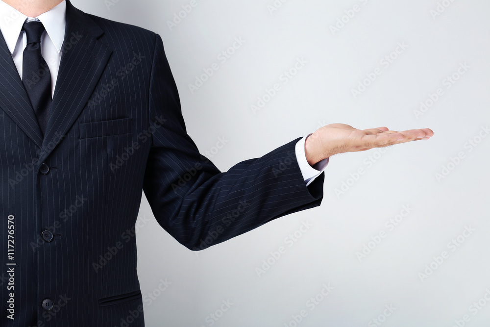 Businessman gesturing with his hand on grey background Businessman gesturing with his hand on grey background