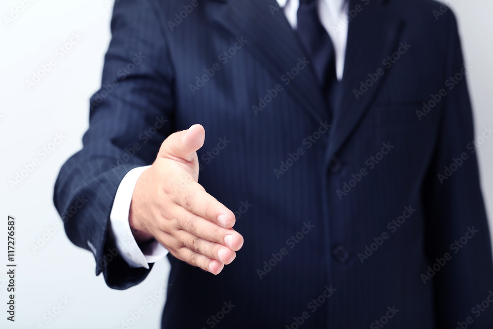 Businessman gesturing with his hand on grey background
