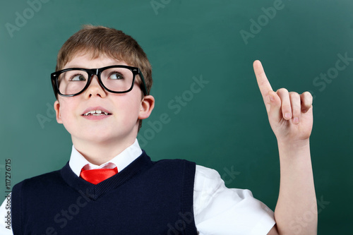 Young boy standing near the blackboard, close up