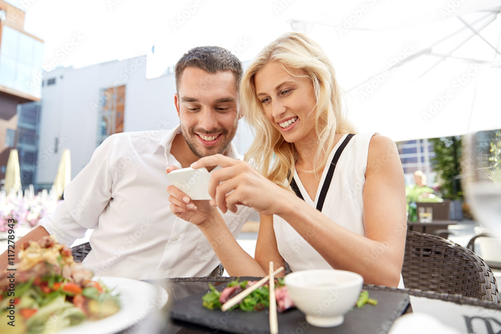 happy couple with smatphone at restaurant terrace happy couple with smatphone at restaurant terrace