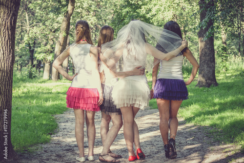 Beautiful bride and happy bridesmaids celebrating hen-party.Happy young hipster girls having fun at bridal shower, wearing colorful fluffy skirts and white t-shirt outdoors in city park on a sunny day