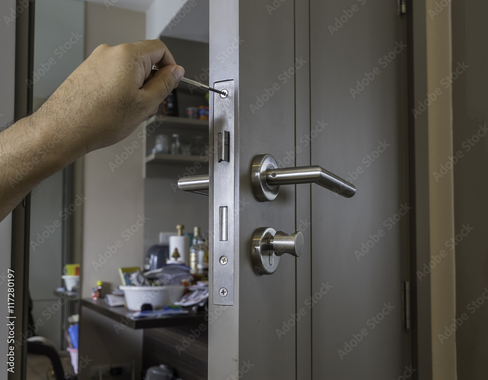 locksmith is repairing the door in room by screwdriver - can use to display or montage on product locksmith is repairing the door in room by screwdriver - can use to display or montage on product