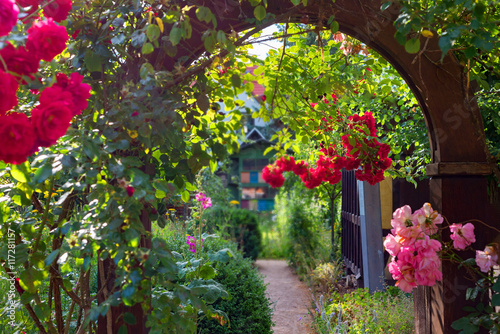 Vászonkép Flower gate arch garden entrance rose blooming path colorful bee hive background