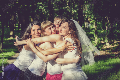 Beautiful bride and happy bridesmaids celebrating hen-party.Happy young hipster girls having fun at bridal shower, wearing colorful fluffy skirts and white t-shirt outdoors in city park on a sunny day