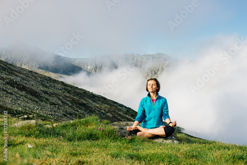 Young girl in sportswear meditates and practices yoga on a background of mountains. Romania