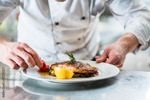 Koch mit Sorgfalt beim Garnieren eines Gerichts, Fisch mit Gemüse