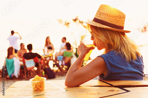 Young woman drinking beer in a beach bar photo