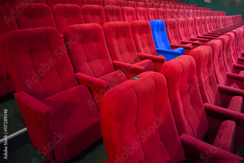 Blue chair between rows of red seats