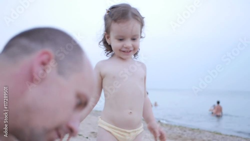 Child Playing on the Beach while Father Show her Sand and Girl Smiling