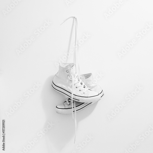White sneakers hanging on white background