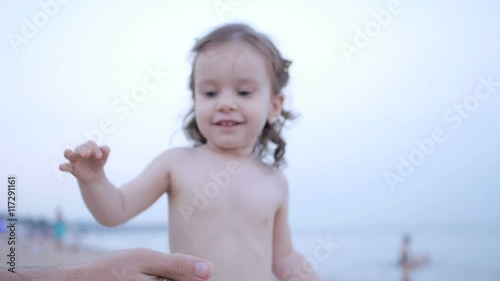 Child Playing on the Beach while Father Show how Sand Pours from Hands