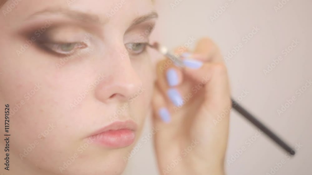 Makeup artist applies eye shadow. Beautiful woman face. Perfect makeup. Close up shot Makeup artist applies eye shadow. Beautiful woman face. Perfect makeup. Close up shot