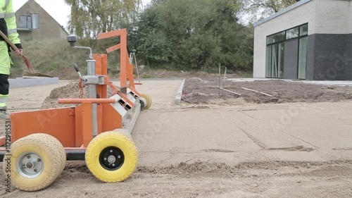 leveling machine preparing the sand before lay out of pavement stones photo