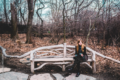 Girl sitting on a bench at the Central Park in Manhattan, New Yo