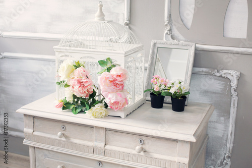 Fotografi dresser with flowers in a light classical interior