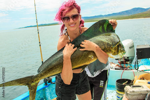 Young fisherwoman on a boat in her arms a big fish Dorado 15 lb, Baja de los Muertos, California Sur, Mexico, America.