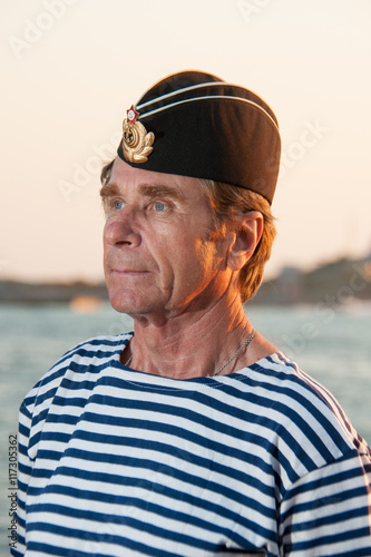 man standing in garrison cap and striped vest on the background © mikhasik