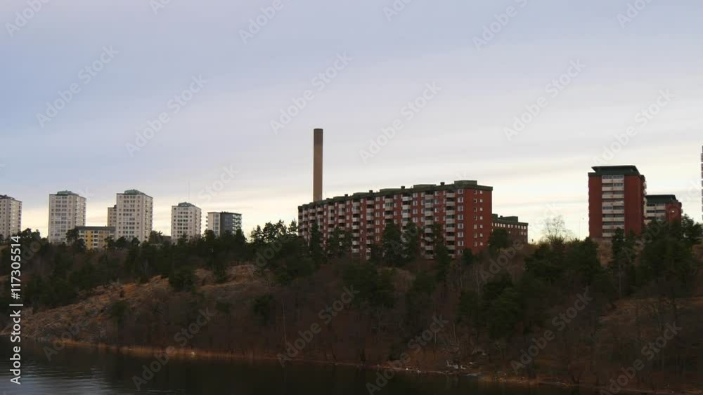 View from a boat to a river bank with red brick house and other buildings as a background View from a boat to a river bank with red brick house and other buildings as a background