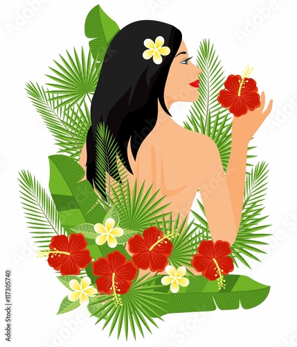 Beautiful girl with a flower in her hair. branches and leaves of tropical plants.