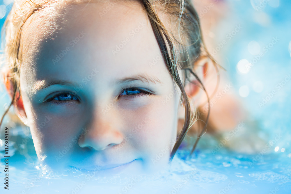 Portrait of cute little girl in blue big inflatable pool outdoors