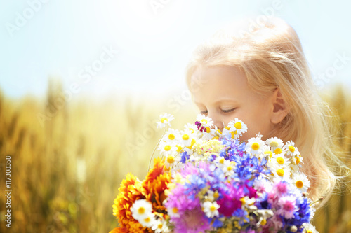 Little girl with bouquet of flowers in the field photo