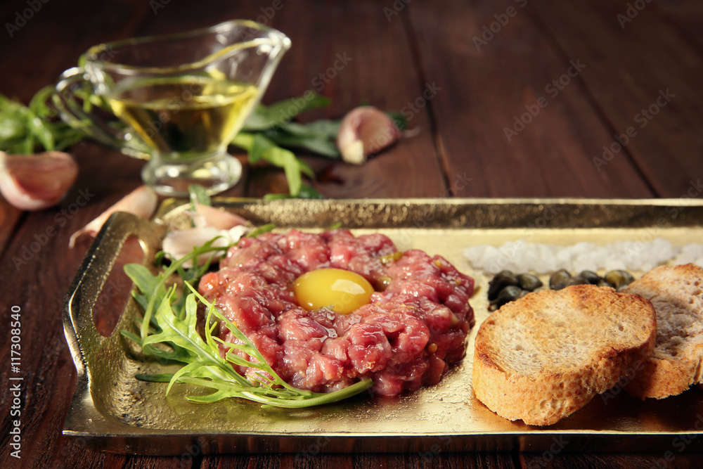 Steak tartar with chopped onion and pickles on a tray
