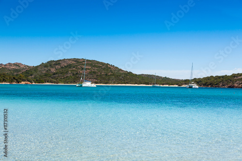 Boats mooring in the turquoise water of Rondinara beach in Cors