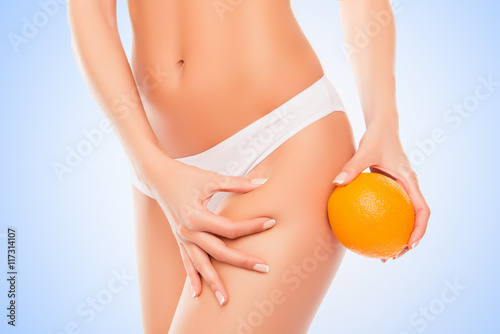 Woman in white panties holding orange near hip and checking fat