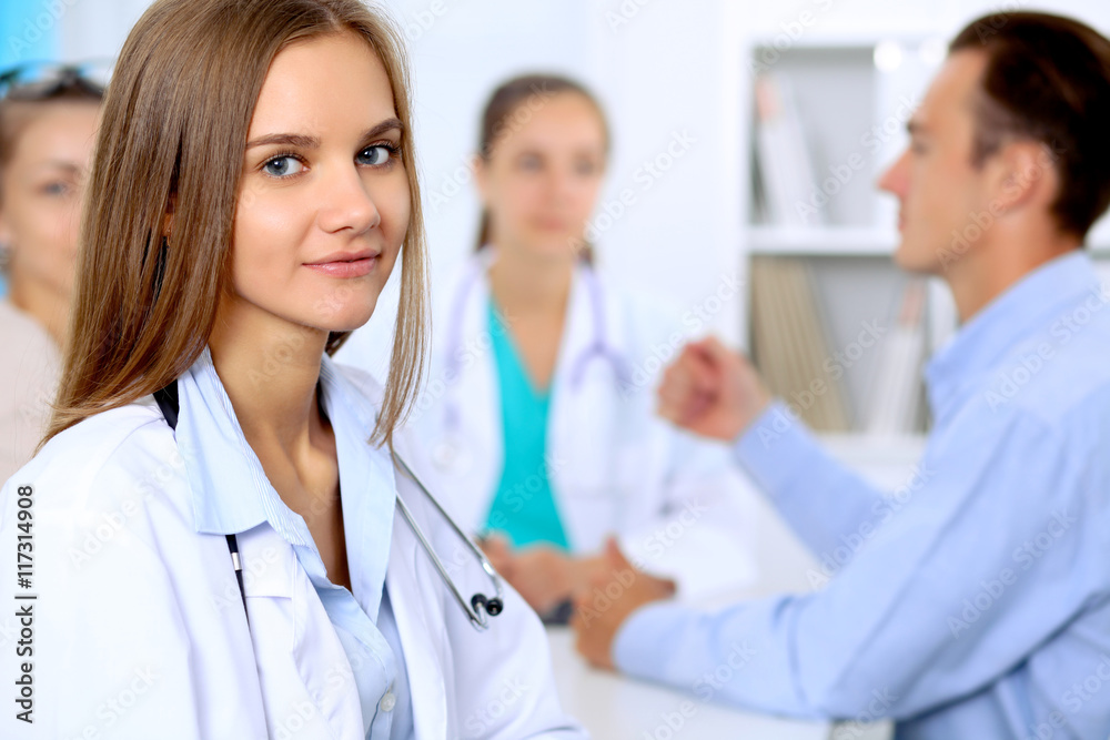 Happy doctor woman with medical staff at the hospital sitting at the table and discussing medical history Happy doctor woman with medical staff at the hospital sitting at the table and discussing medical history