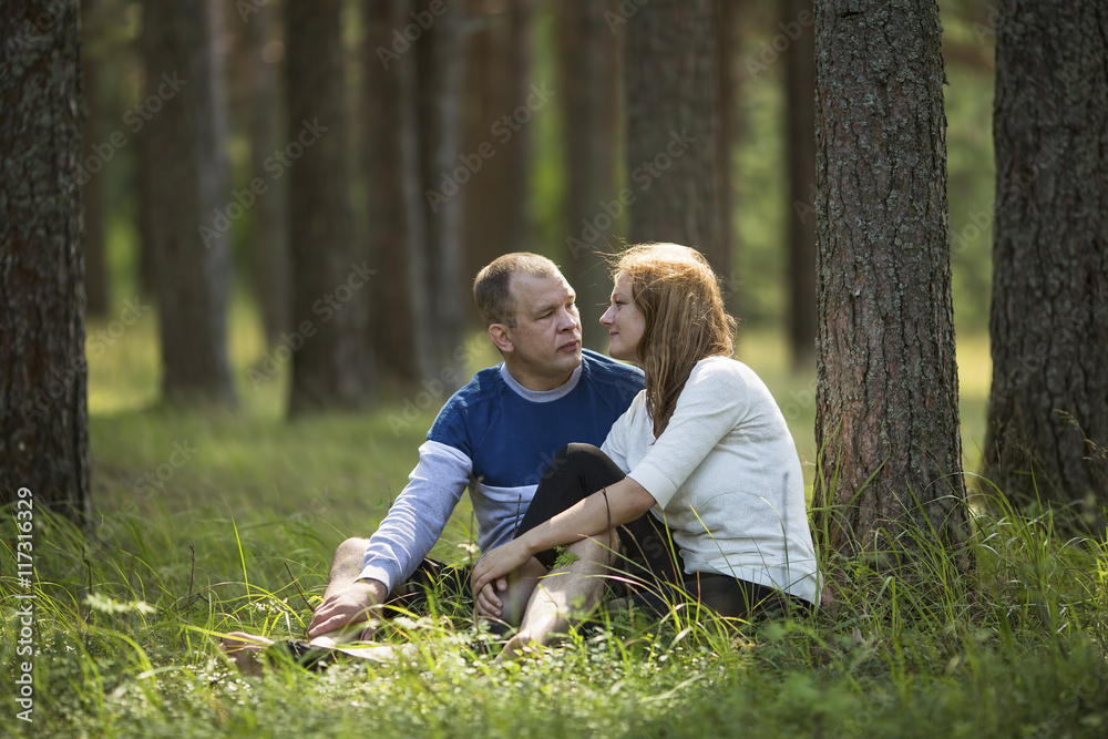 Fototapeta premium Young couple sitting in the grass near the tree in the Park . Honeymoon.