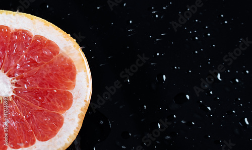 Half grapefruit citrus fruit on black background with water